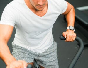 person cycling on a stationary bike in a modern fitness studio - will an exercise bike help lose weight