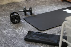 Minimal home gym setup with a mat, resistance bands, and a pair of dumbbells